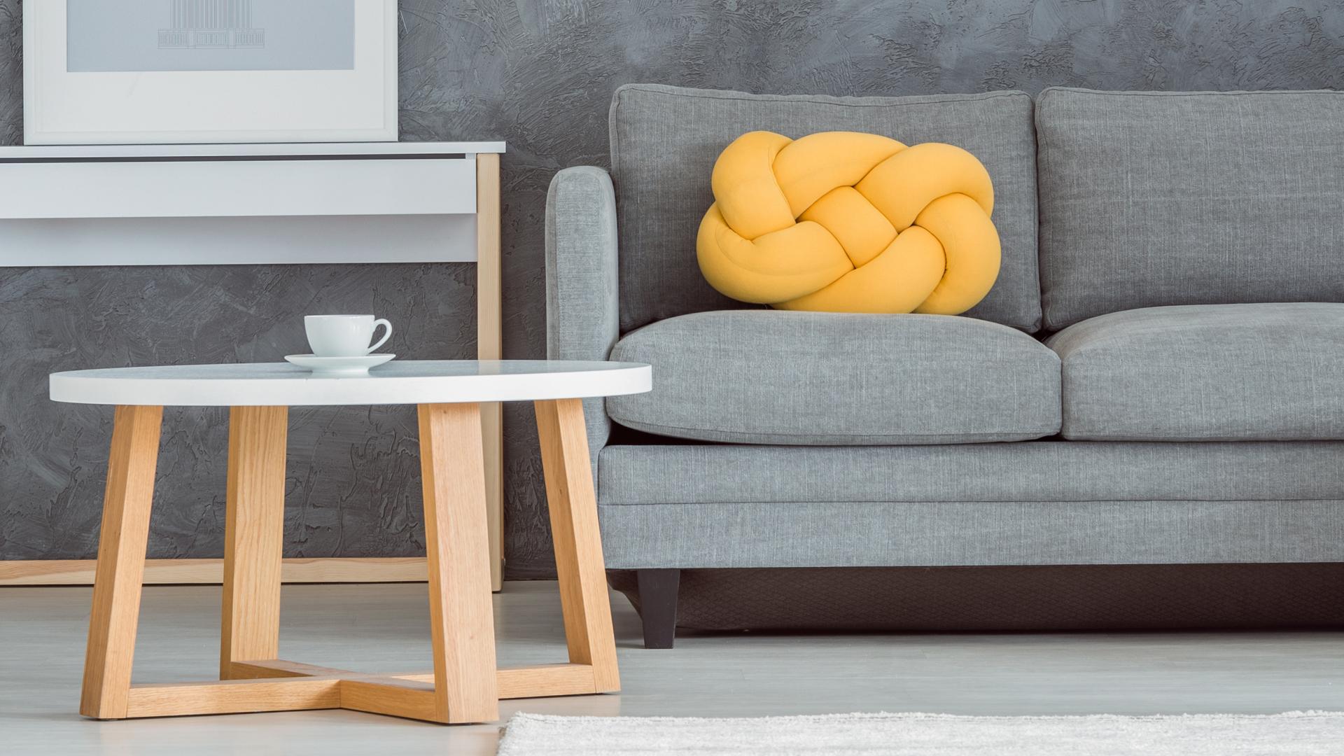 Interiörbild på ett vardagsrum. På bildens syns en del av en grå soffa och ett litet soffbord med en kaffekopp på.