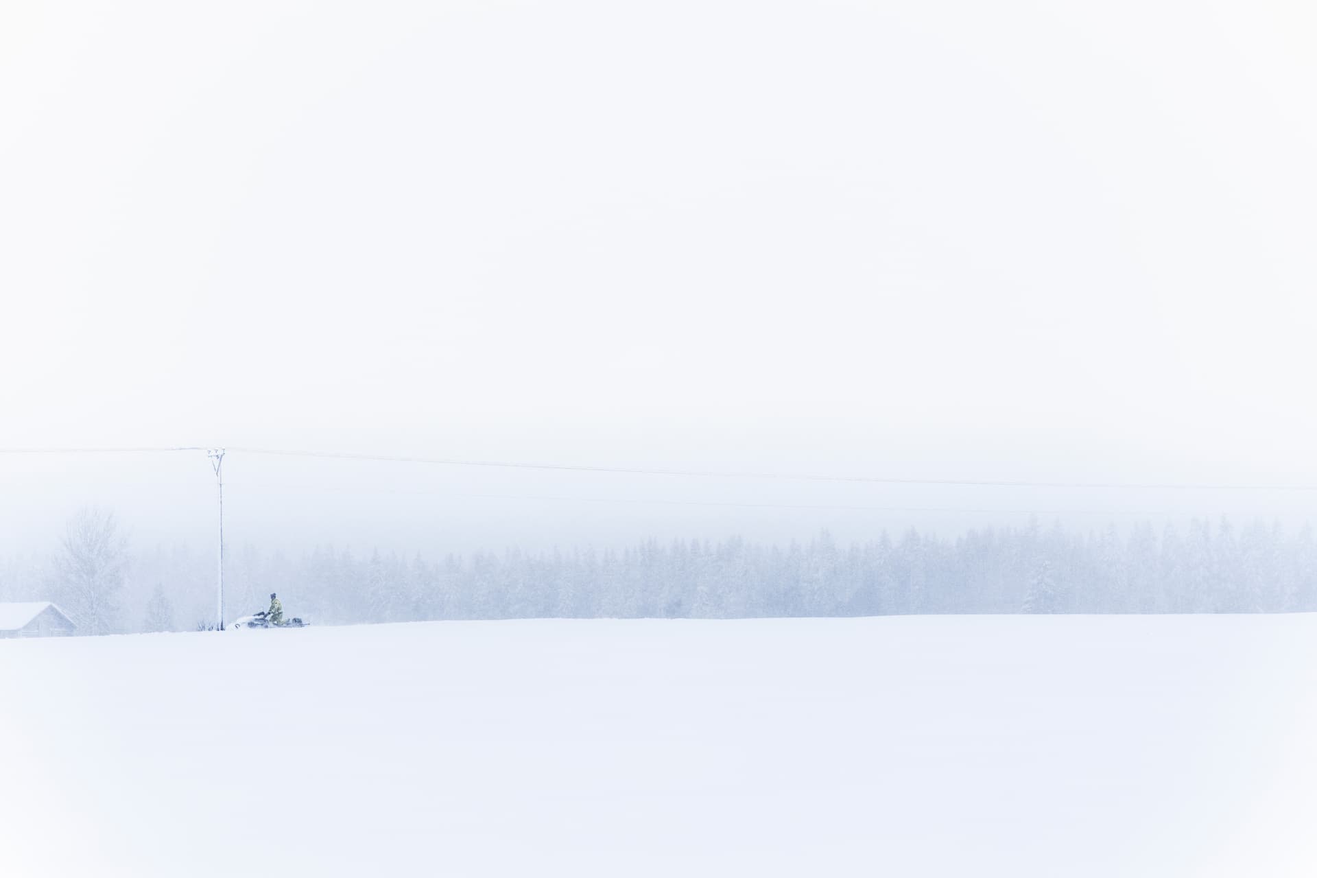 En medarbetare på Jämtkraft kör skoter längs elnätet en snöig vinterdag.