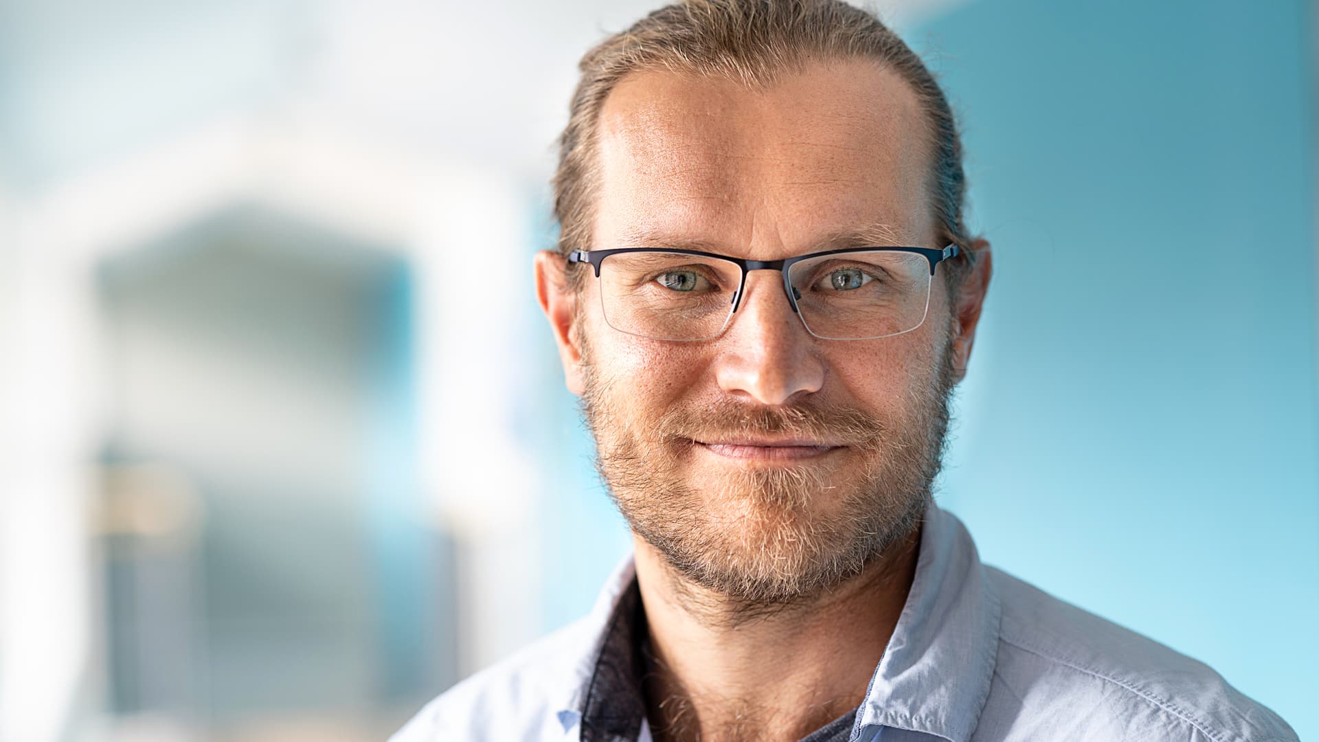 En man med glasögon och blå skjorta