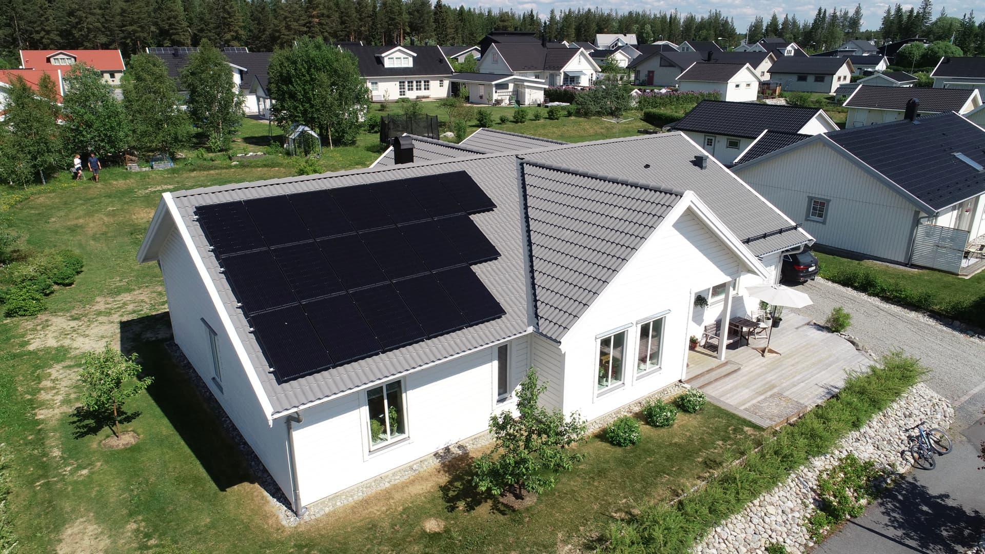 Solceller monterade på taket på en vit villa i ett bostadsområde.