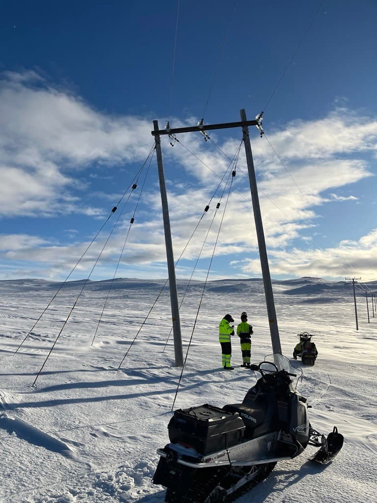 Elledning i snötäckt fjällandskap, två skotrar och två montörer.