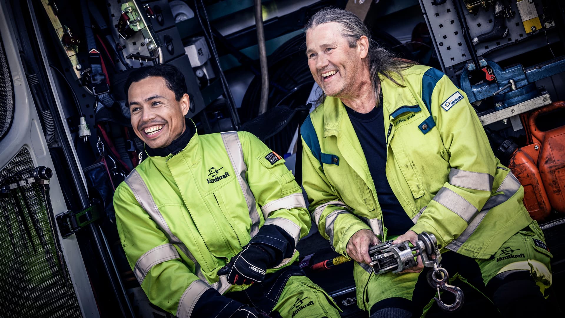 Två glada män i arbetskläder sitter i en mätbuss.