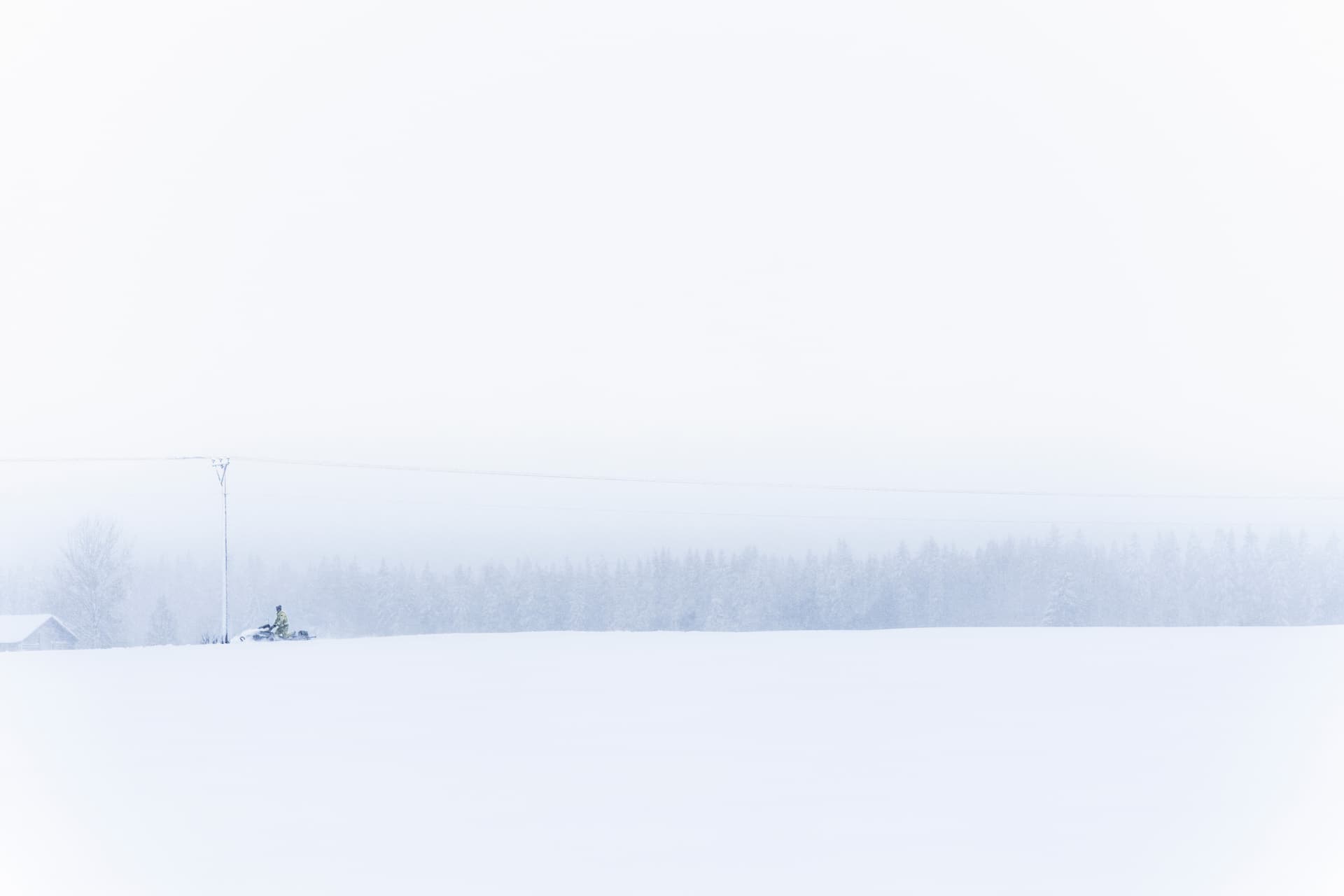 En medarbetare på Jämtkraft kör skoter längs elnätet en snöig vinterdag.