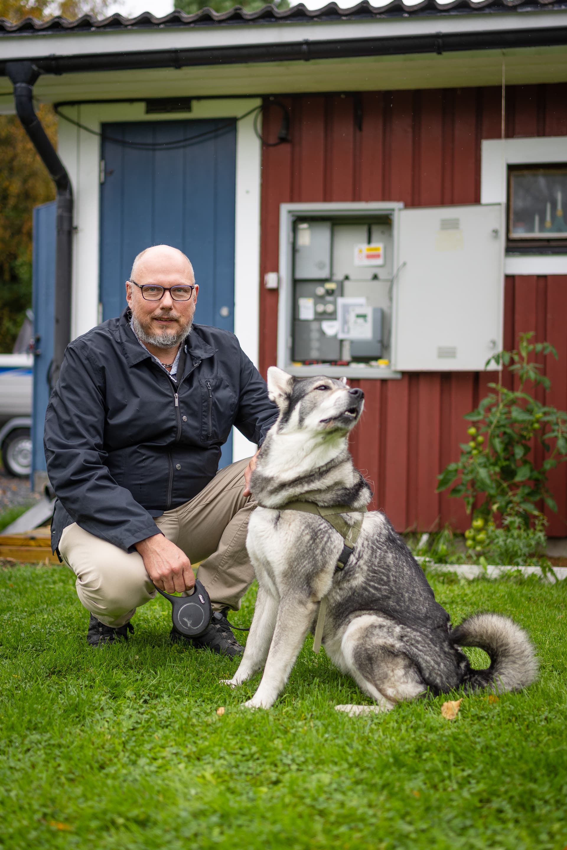 Jörgen Nykvist sitter utanför sitt hus tillsammans med sin hund.