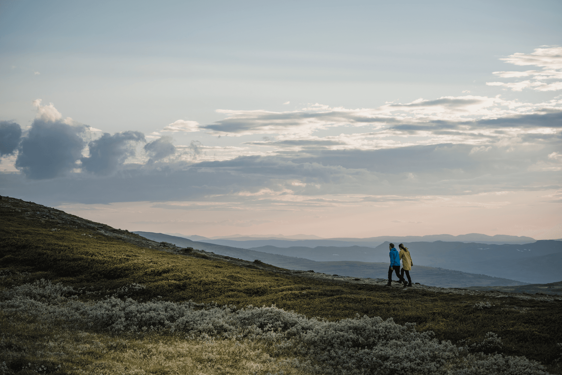 Två personer går tillsammans på ett fjäll en höstdag.