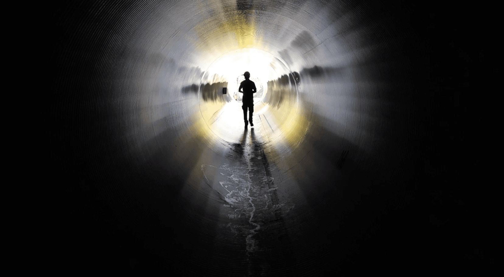 En person går i en mörk tunnel.