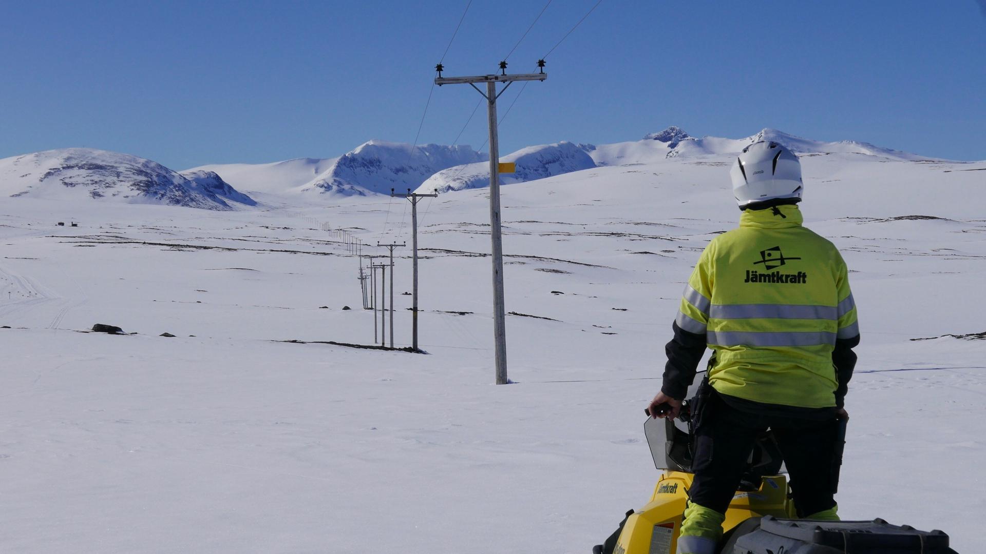En medarbetare på Jämtkraft kör skoter på fjället Sylarna längs en elledning.