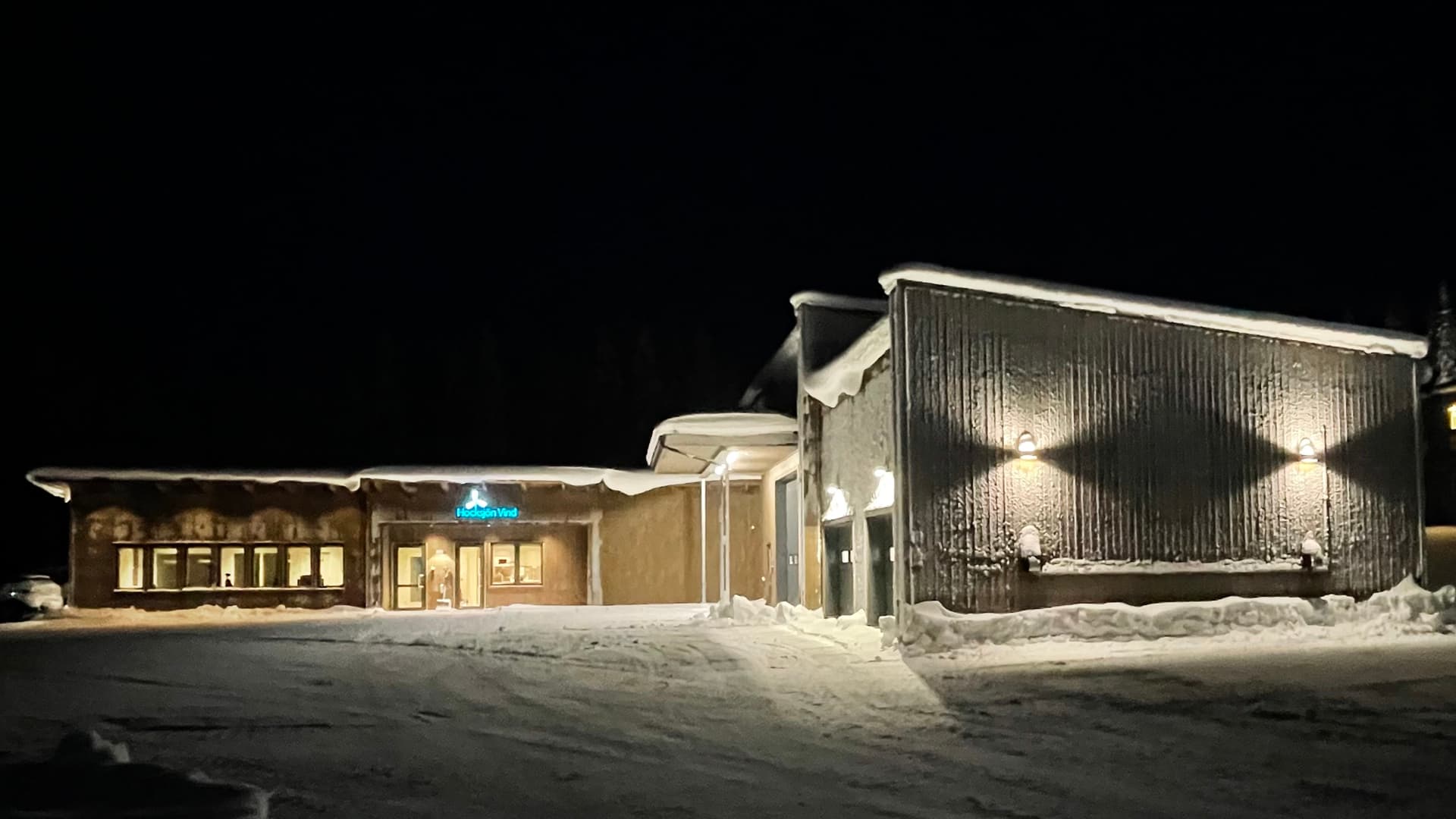 Exteriörbild på en upplyst kontorsbyggnad i mörker.