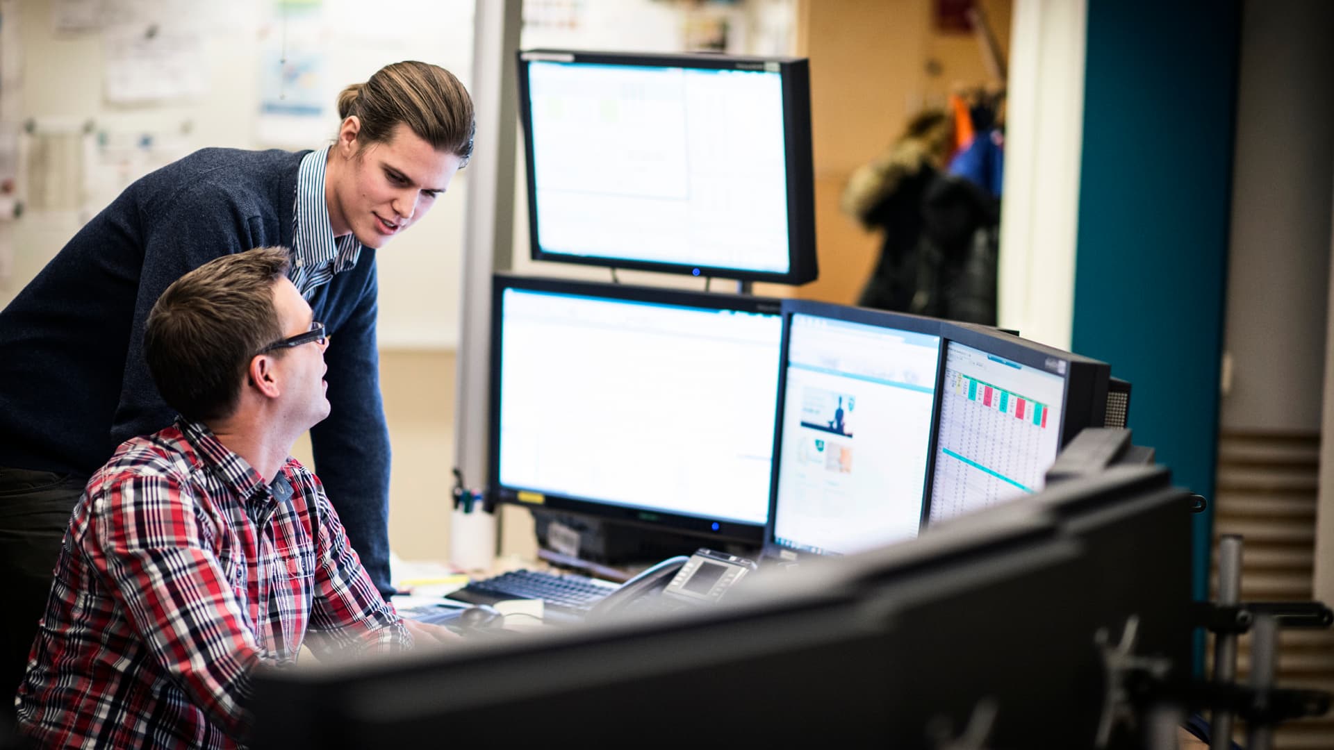 Två personer tittar på flera dataskärmar