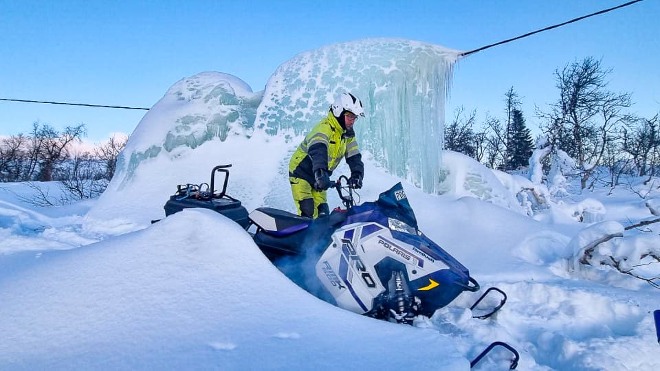 En medarbetare på Jämtkraft kör skoter till en nedisad elledning.