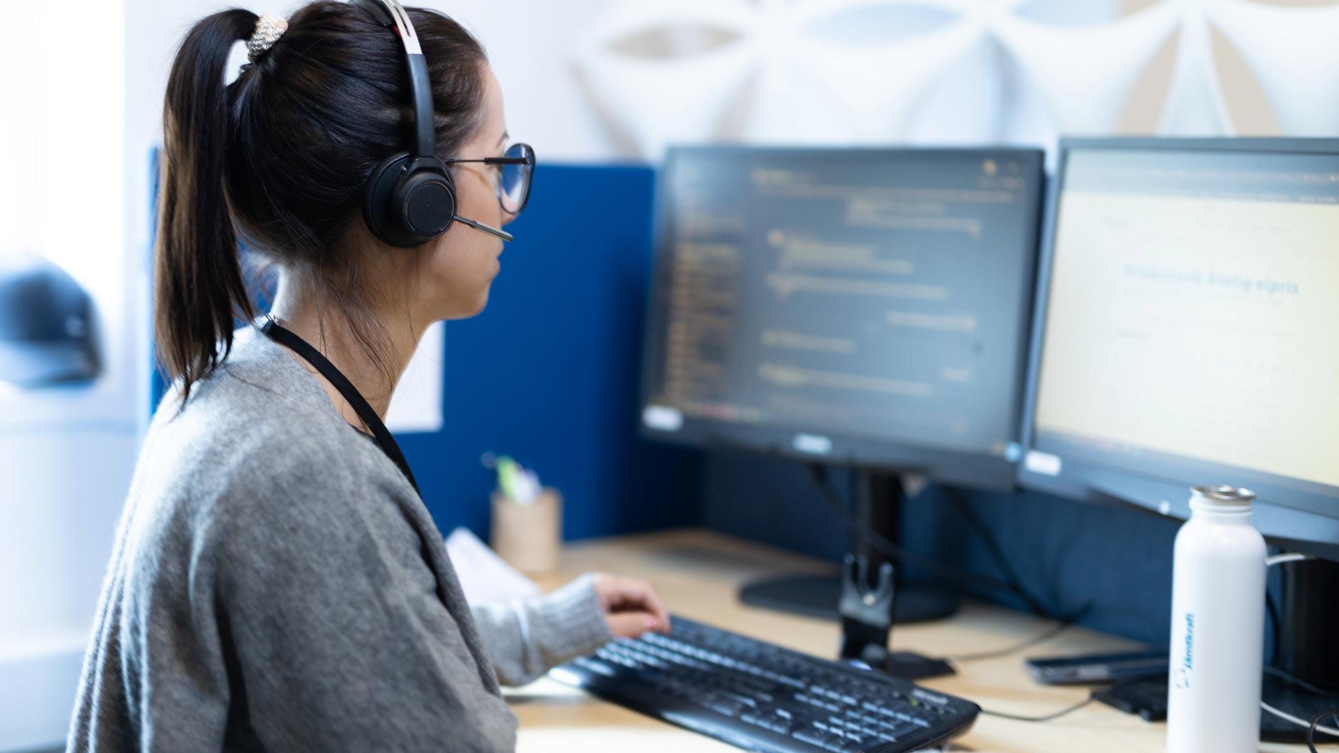En medarbetare på kundservice talar i telefon vid datorskärmar