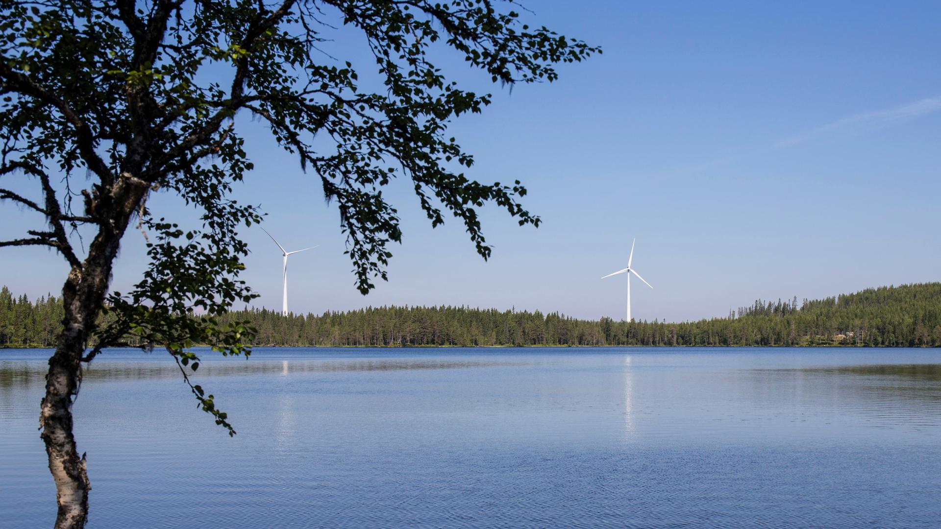 Vy över ett vattendrag med mullbergs vindkraftverk i bakgrunden.