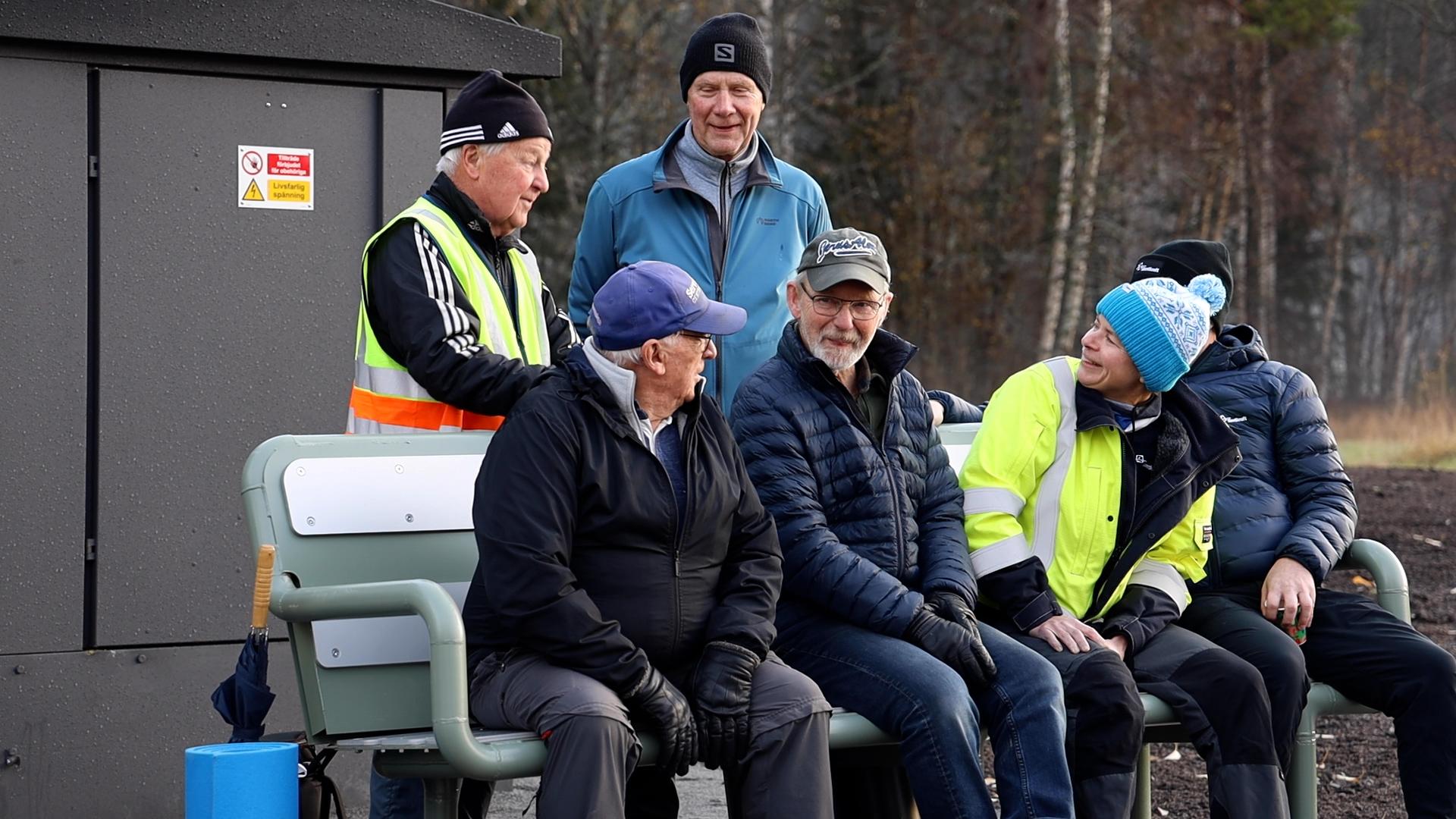 Jämtkrafts vd Ylva Andersson sitter tillsammans med fyra män på en värmebänk som värms upp av fjärrvärme.