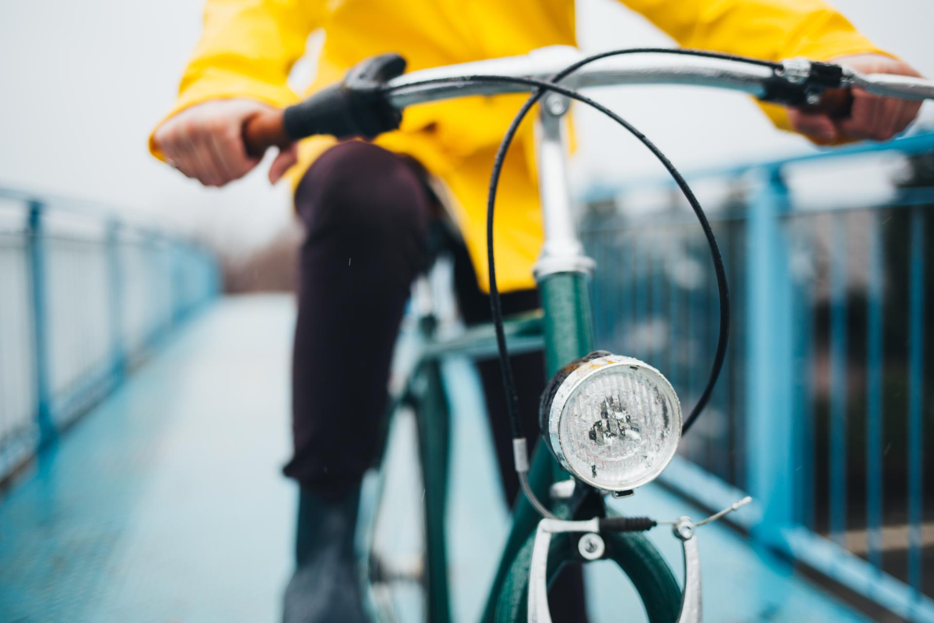 Närbild på en person i gul jacka som cyklar på en gammal cykel.