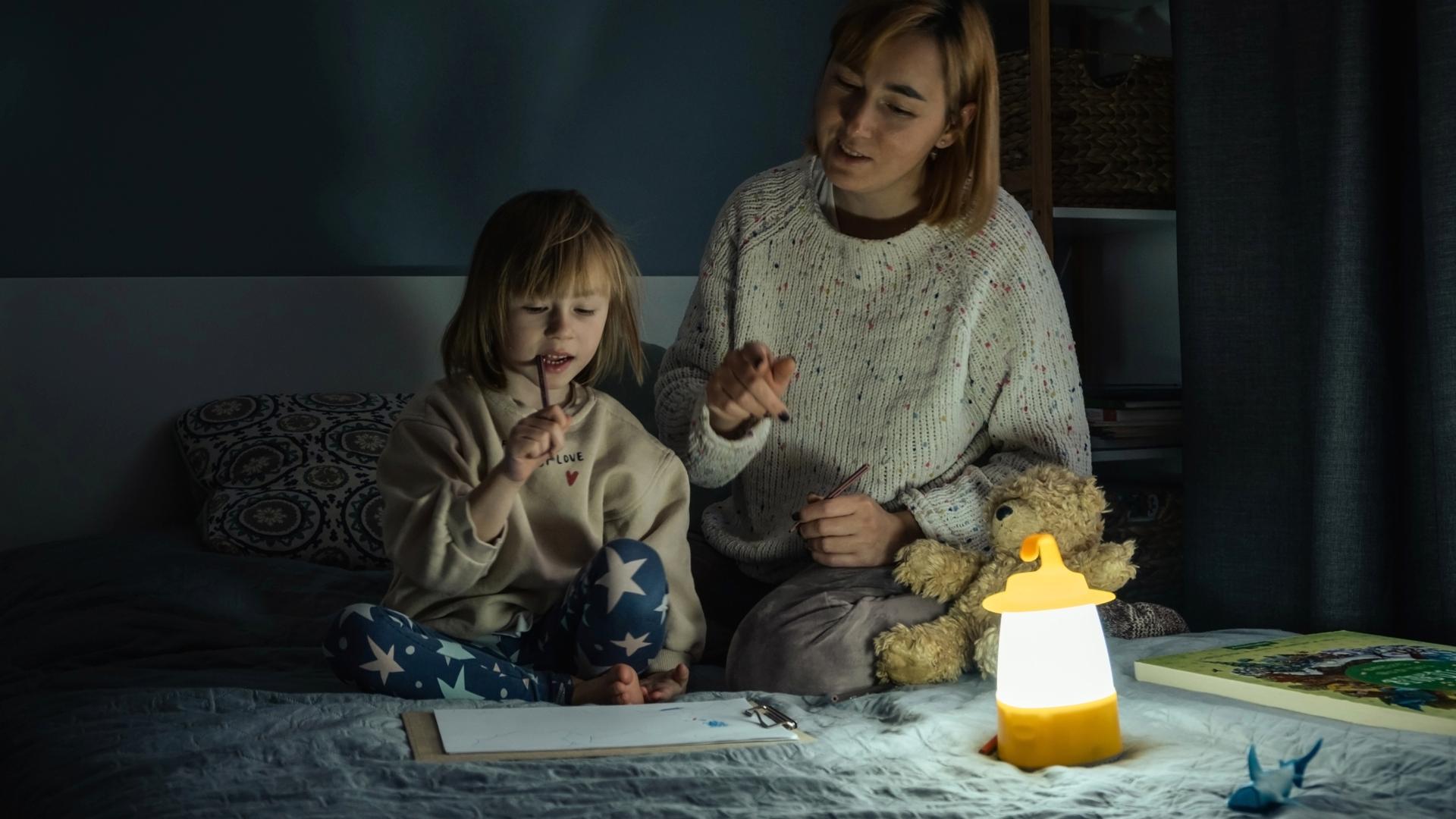 Ett barn och en kvinna sitter i sängen men låg belysning