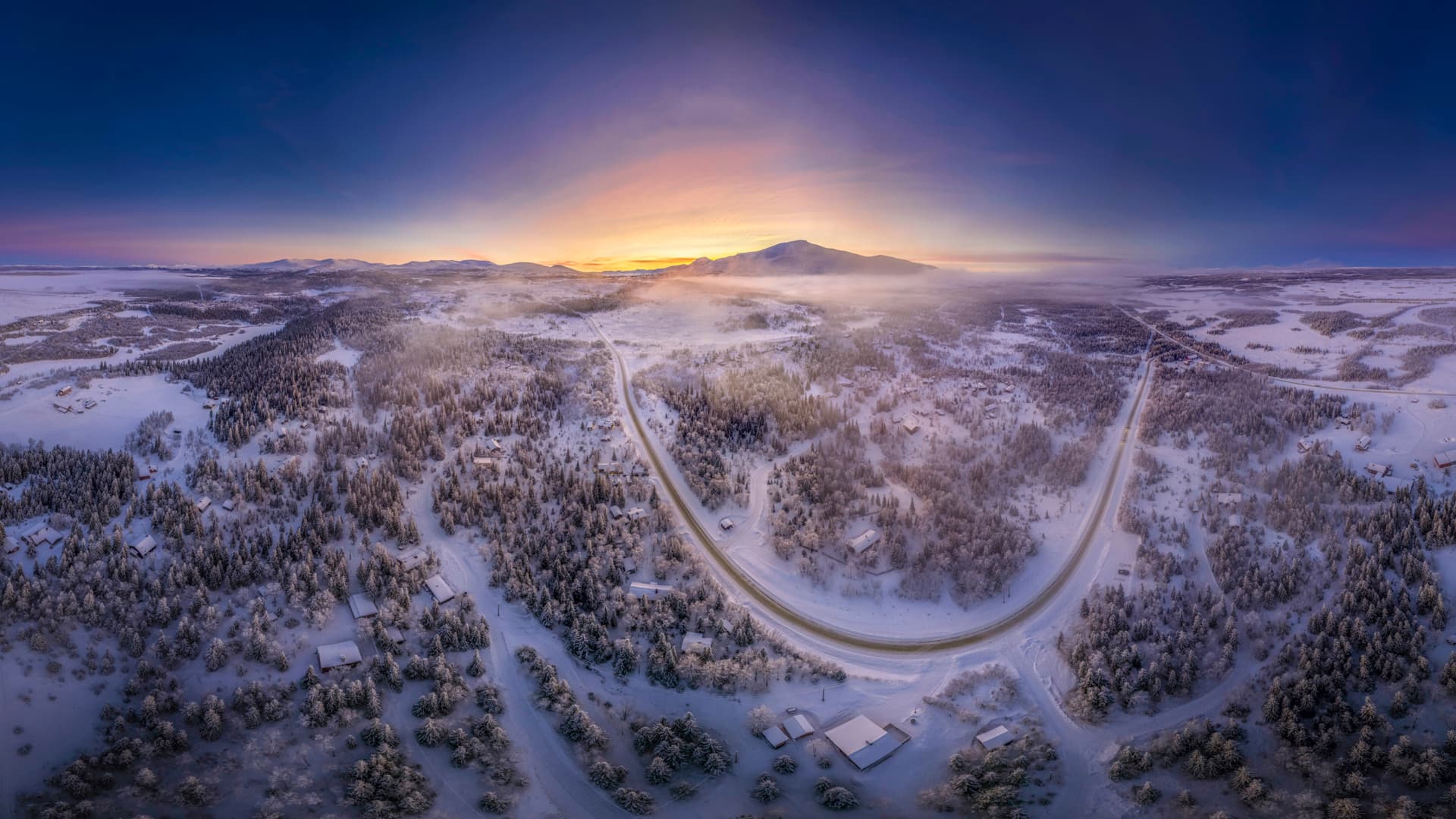 Solnedgång över ett vintrigt landskap.