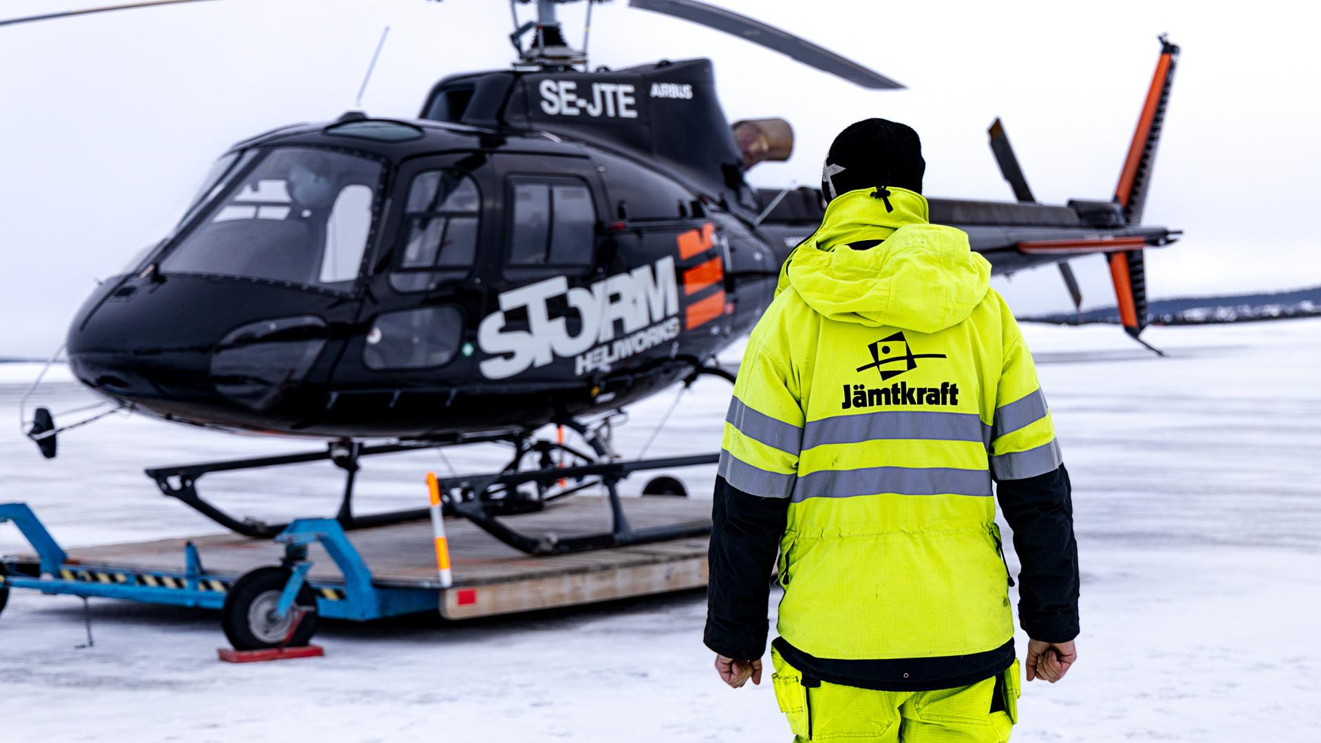 En medarbetare på Jämtkraft står framför en helikopter.