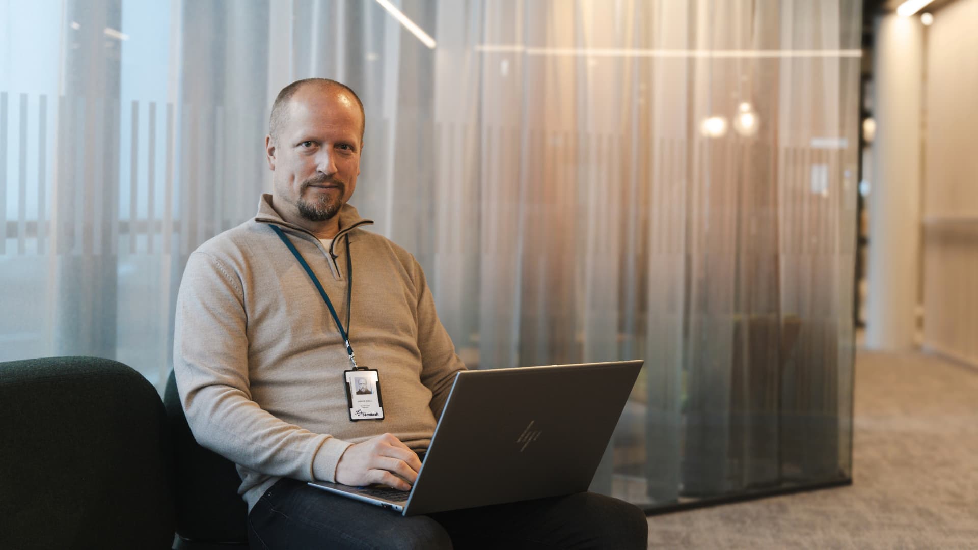En man som sitter i en soffa med en bärbar dator.
