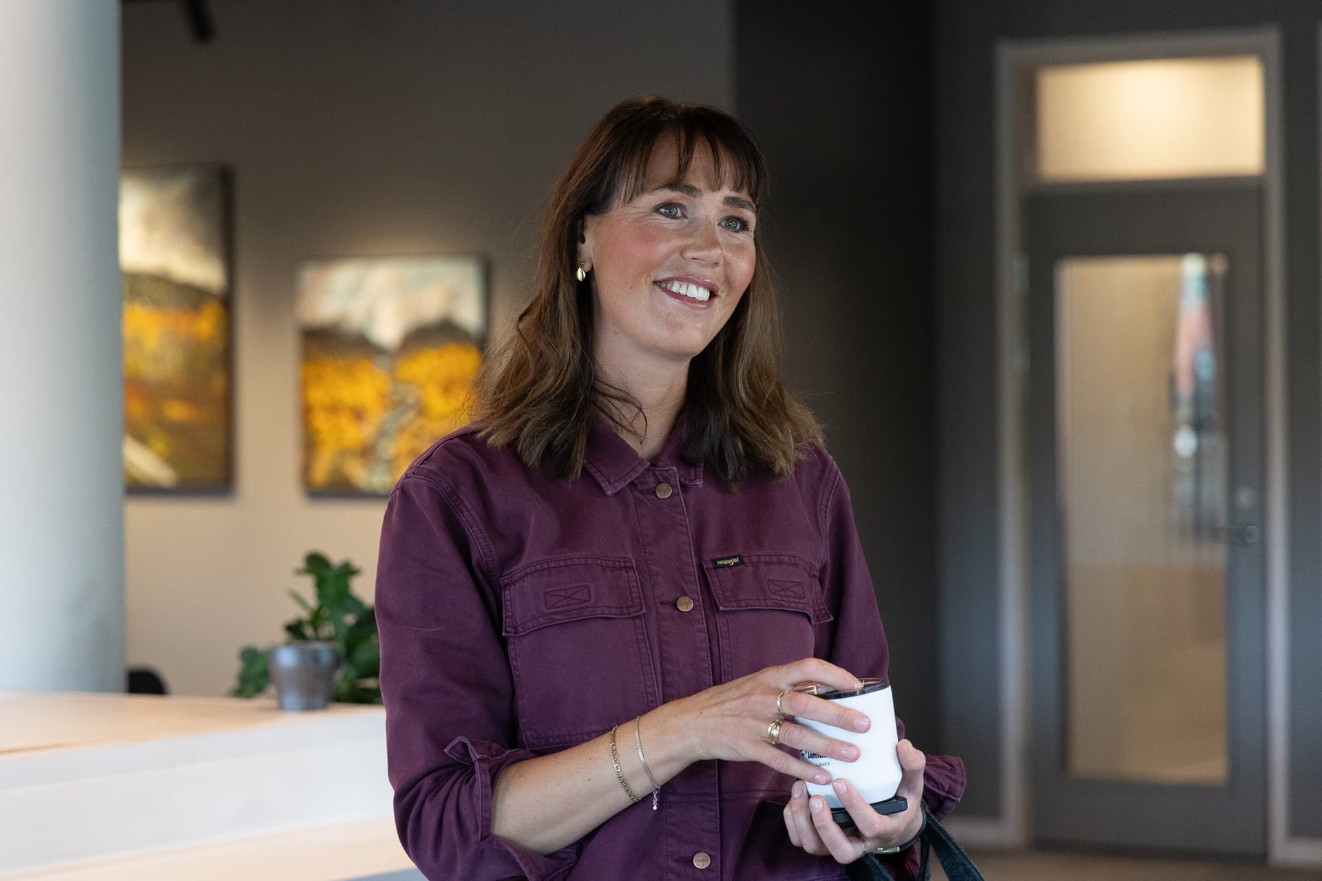 En leende kvinna håller i en kaffekopp.