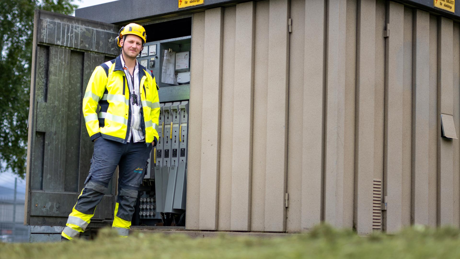 Måns Olsson, medarbetare på Jämtkraft, står framför en elnätsstation.