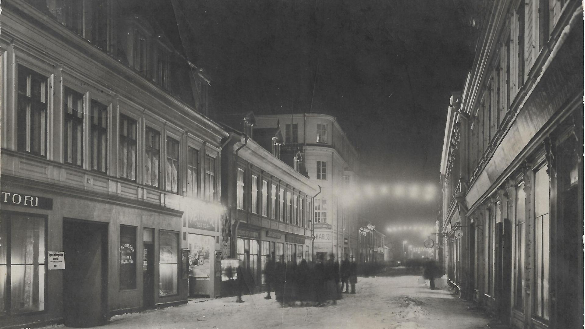 Kvällsbelysning över Storgatan i Östersund en vinterdag i början av 1900-talet.