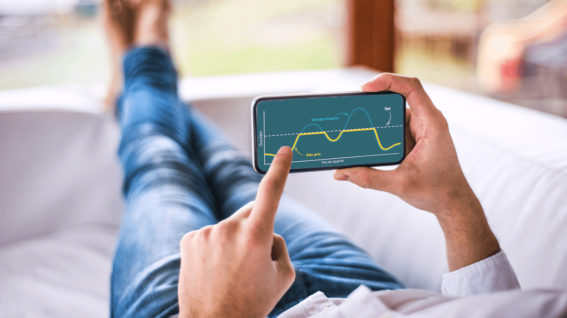 En man ligger på soffan och tittar på Jämtkrafts app i sin telefon.