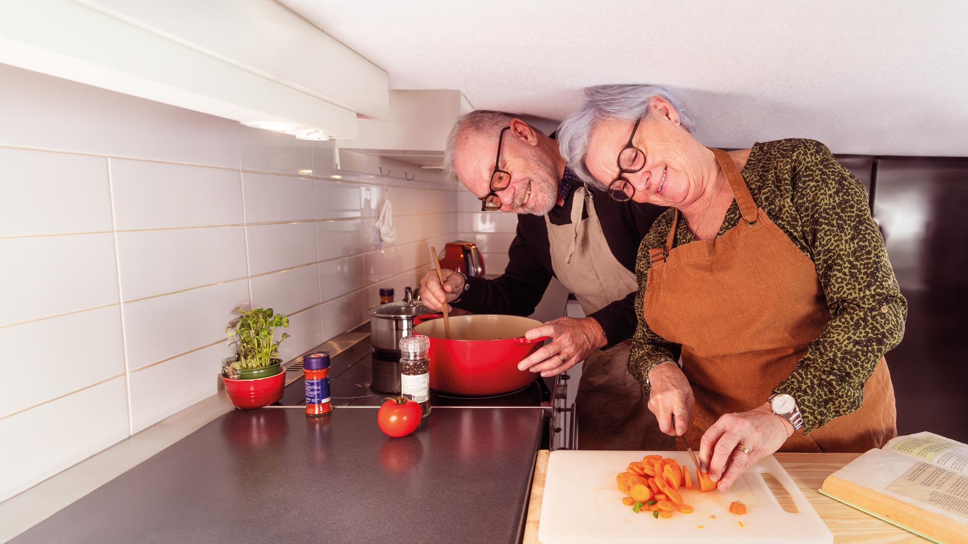 Ett par lagar mat i sitt kök med ett väldigt lågt tak