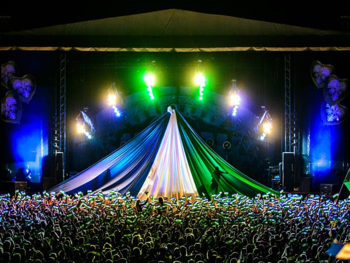 Ett folkhav framför stora scenen på Storsjöyran. På scenen hänger tyger i Jämtlands färger blått, vitt och grönt.